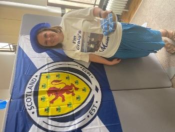 Woman standing beside a Scotland flag wearing a t-shirt that reads 'I'm Craig's mum'