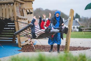 A woman with three children on a hammock swing in a play park