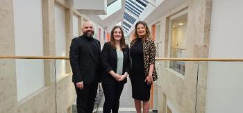 Children’s Services manager Kevin Smith, Minister for Children, Young People and The Promise, Natalie Don-Innes, and assistant director for The Fostering Network Anne Currie stand together in a row inside Johnstone Town Hall, a bright, airy building.