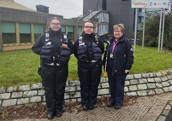 Three female uniformed wardens stand in front of community safety hub building