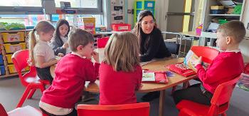 Five Bargarran Primary School pupils doing peer reading with teacher at a round table in their classroom