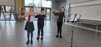 Three Bargarran Primary School pupils playing flute in the school multi-use hall.